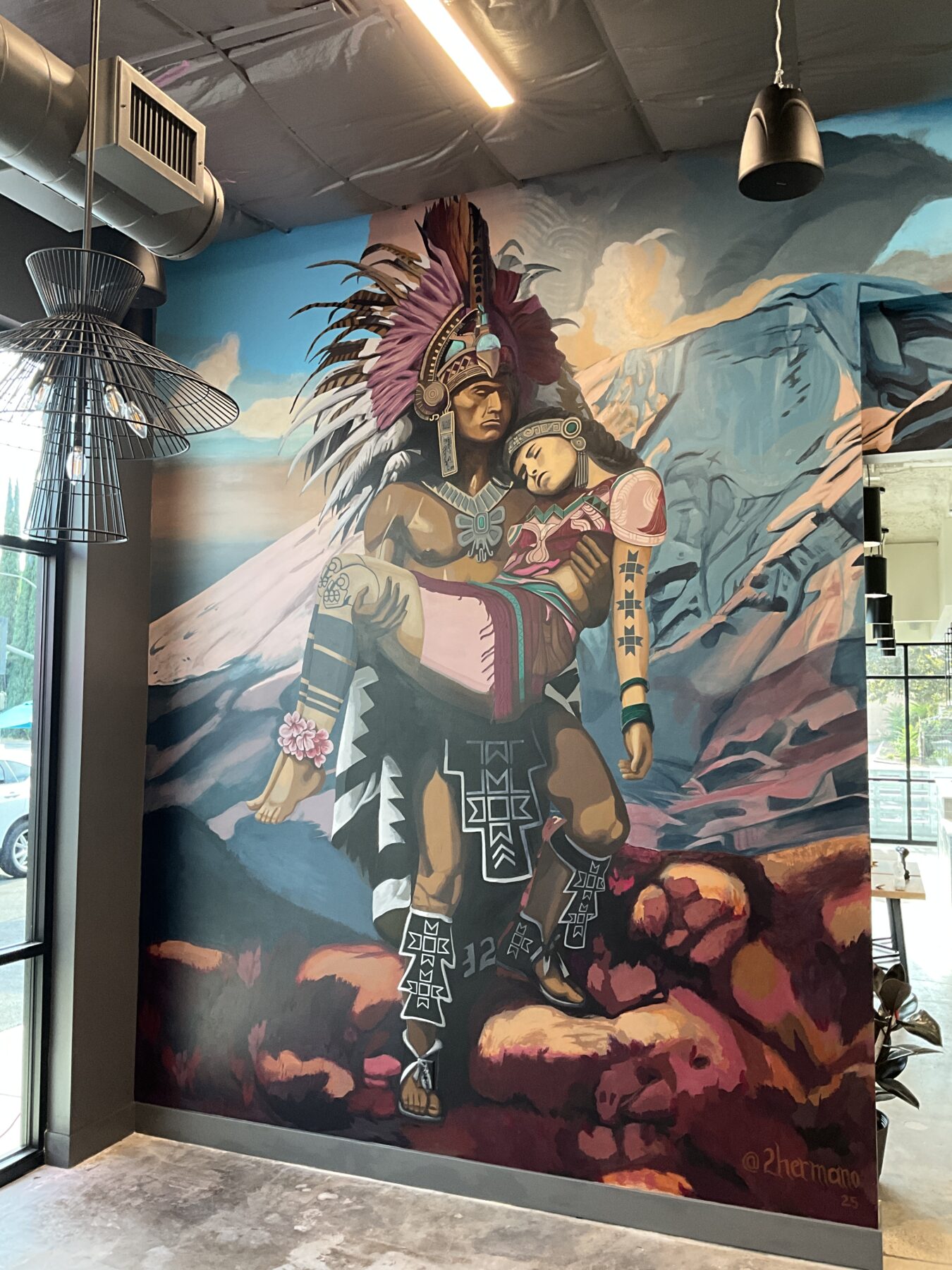 Painting by Chicano artist 2hermano. Aztec warrior hold princess in his arms. Mexican muralist.