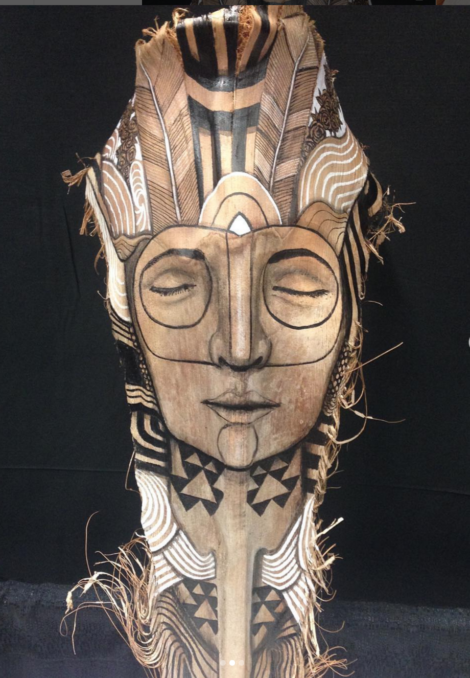 A palm frond mask of a serene woman with her eyes closed